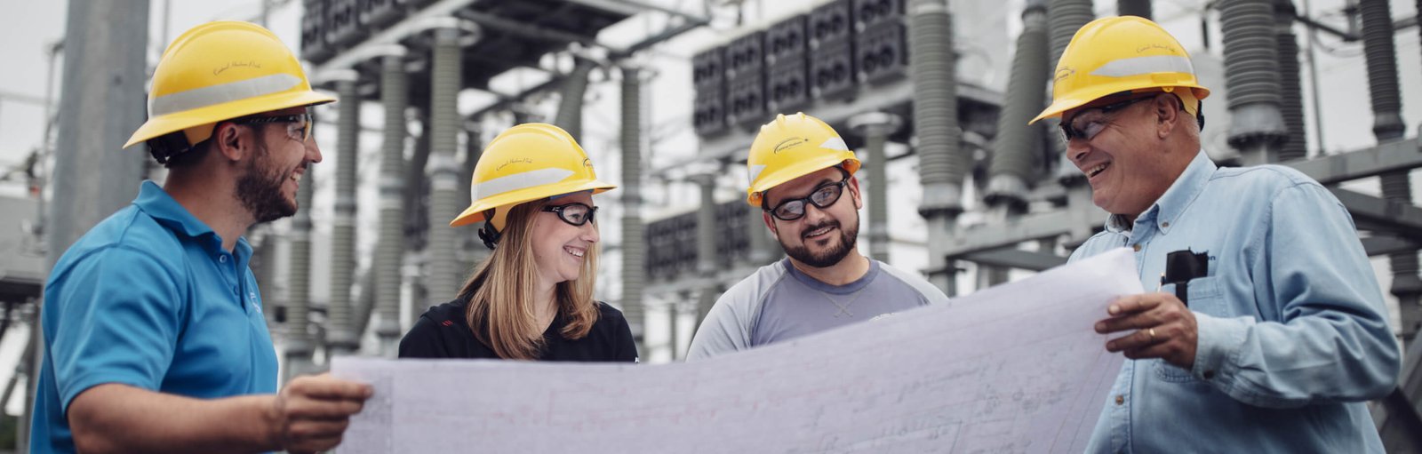 OVP_HeaderIMG A woman and men wearing safety hats and viewing a large paper document