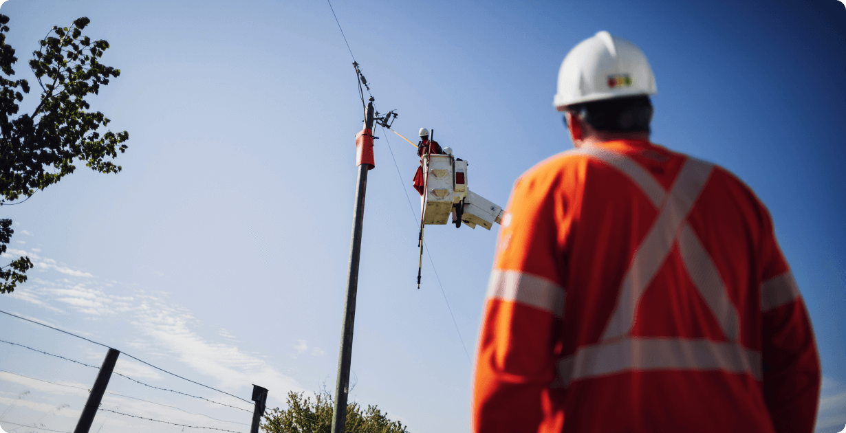 AverageReturn Man in safety gear spotting a lineman in a truck bucket repairing a power line